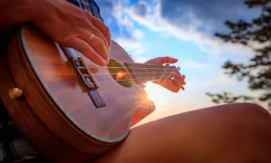 Słońce zachodzi, a ja uczę się, jak się gra na ukulele. Dźwięki instrumentu unoszą się w powietrzu.