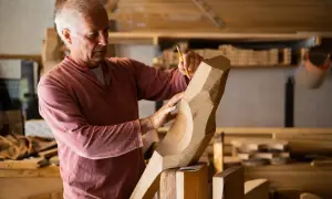 Saverio Pastor, scultore del legno, con matita e mani esperte definisce le forme di un'opera in lavorazione.