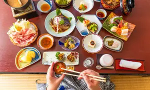 En person njuter av en utsökt japansk måltid med många små rätter, som sashimi, grillad fisk och grönsaker. En härlig upplevelse av japansk street food.