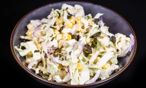 Frischer Chinakohl Salat mit Mais, roten Zwiebeln und Kürbiskernen in cremiger Soße.