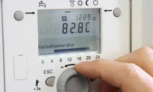 Hand stellt die vorlauftemperatur gasheizung ein. Kesseltemperatur 82.8°C.