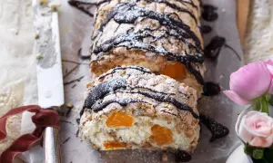 En läcker budapestbakelse med vispgrädde, frukt och chokladdrizzle, pudrad med florsocker.