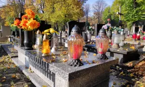 Cmentarz jesienią. Znicze i kwiaty na grobach. Zastanawiasz się, ile kosztuje miejsce na cmentarzu w 2026 i opłata prolongacyjna?