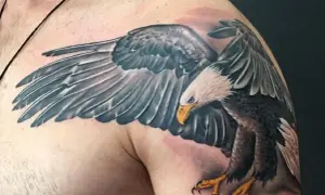 Tatuaż białego orła z rozpostartymi skrzydłami na ramieniu.