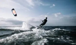 Kitesurfer w akcji, pokonujący fale. Dynamiczne sporty wodne w pełnym blasku.
