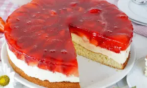 Erdbeerkuchen mit Biskuitboden, Vanillepudding und frischen Erdbeeren unter rotem Tortenguss. Ein saftiges Stück wartet!