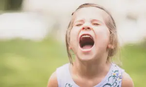 Małe dziecko nie radzi sobie z emocjami, krzyczy z otwartymi ustami.