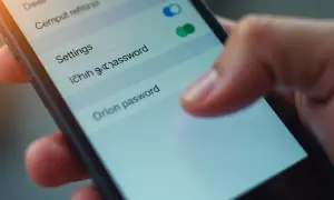 Palec dotyka ekranu telefonu, wybierając opcję "Orion pasword". Dowiedz się, jak zmienić hasło w telefonie, aby zwiększyć bezpieczeństwo.