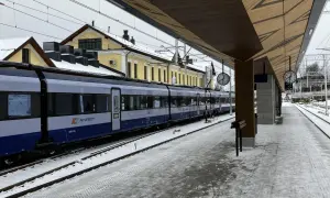 Pociąg PKP Intercity na stacji w Żaganiu, zimowy dzień. Zielona góra w oddali, śnieg na torach i peronie.