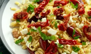 Pyszna sałatka z makaronu orzo, suszonych pomidorów, oliwek, sera feta i świeżej bazylii.