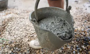 Cubeta con mortero de cemento fresco, lista para ser vertida. El suelo está cubierto de grava.