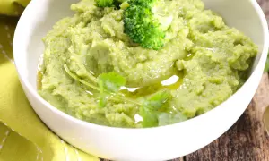Un bol de purée de brocolis onctueuse, garnie de fleurettes de brocolis et d'un filet d'huile d'olive.