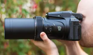 Un uomo usa una fotocamera bridge con zoom 125x. Scopri cosa sono le fotocamere bridge e la loro versatilità.