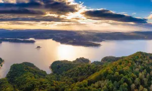 Zachód słońca nad jeziorem Solina. Zalesione wzgórza i łagodne solina szczyty w jesiennych barwach.