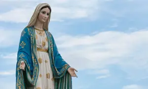 Kamienna figura Matki Bożej w błękitnym płaszczu ze złotymi zdobieniami, jakby wznosiła się do nieba podczas litanii do Matki Bożej.
