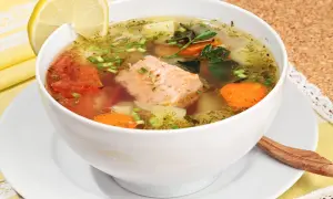 Aromatyczna, prawdziwa zupa rybna z łososiem, pomidorami, marchewką i ziemniakami, ozdobiona plasterkiem cytryny i natką pietruszki.