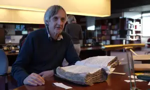 Un homme consulte un livre ancien, peut-être une source pour les meuse archives en ligne.