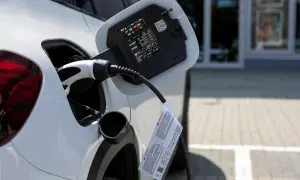 Biały samochód podłączony do ładowania. To przyszłość motoryzacji, czyli przerabianie samochodów na elektryczne.