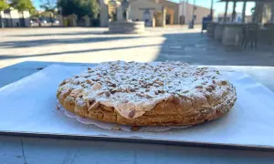Tarte aux pignons de Gruissan, saupoudrée de sucre glace, sur une table ensoleillée.