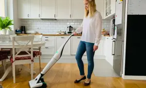 Kobieta sprząta kuchnię nowoczesnym odkurzaczem Vorwerk.