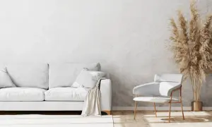 Un salon moderne avec un canapé blanc, un fauteuil design et un bouquet de pampas sur un mur au motif crépis.