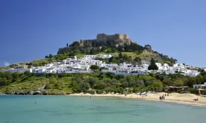 Piękna pogoda na Rodos w październiku. Białe domki Lindos i akropol na wzgórzu, plaża i turkusowe morze.