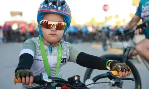 Chłopiec w kasku rowerowym i okularach przeciwsłonecznych, gotowy do jazdy. Czy kask na rower jest obowiązkowy? Ten młody cyklista pokazuje, że bezpieczeństwo jest ważne.
