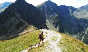 Turystka na grani, podziwia majestatyczne szczyty Tatr Zachodnich. Widok na Rohacze i szlak zapiera dech w piersiach.