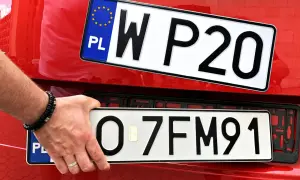 Ręka trzyma tablicę rejestracyjną z napisem "O 7FM91". Obok widać inną tablicę "W P20". To początek ep rejestracja.