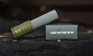Ostrzałka do haczyków z zieloną rękojeścią i kamieniem szlifierskim, obok pudełka z napisem "JUST PUT THE TIP IN".