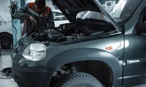 Mechanik wymienia żarówkę w przednim reflektorze Skody Fabii 3.