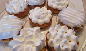 Plusieurs tartelettes garnies d'une crème jaune et surmontées de délicieuse meringue italienne aux formes variées.