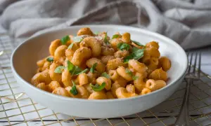 En skål med krämig fetaost pasta, toppad med färsk basilika och riven ost. Enkel och god vardagsmat.