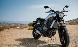 Motocykl stojący na pustynnym, kamienistym podłożu pod błękitnym niebem.