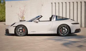 Białe Porsche 911 Targa z otwieranym dachem, z napisem "Targa" na błyszczącym pałąku, stoi na brukowanym podjeździe.