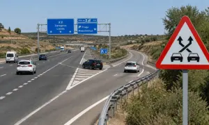 Señal de advertencia de tráfico cruzado, señal p35, en una autopista con varios coches circulando.