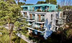 Nowoczesne władysławowo apartamenty przy plaży z widokiem na morze. Balkony z przeszklonymi balustradami i zielone otoczenie.