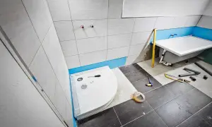 Einbau einer Duschwanne im Badezimmer. Werkzeuge und Rohre liegen bereit.