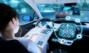 Donna legge un libro mentre l'auto guida da sola, mostrando la tecnologia di guida autonoma livello 4.
