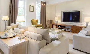 Przytulny pokój 20m2 z wygodną kanapą, fotelem i telewizorem. Jasne kolory i eleganckie dodatki tworzą relaksującą atmosferę.