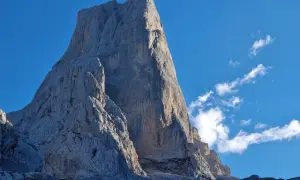 El imponente Urriellu se alza majestuoso bajo un cielo azul, invitando a contemplar el tiempo y la grandeza de la montaña.