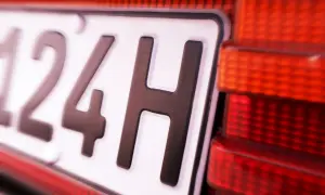 Nahaufnahme eines Nummernschilds mit der Aufschrift "124H". Die rote Rückleuchte des Autos ist daneben zu sehen. Hoffentlich gibt es keine 07-Kennzeichen-Strafe.