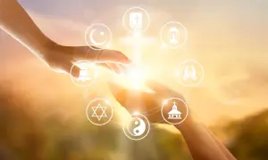Dłonie łączą się, otoczone symbolami różnych religii, odzwierciedlając jedność i poszukiwanie duchowości, która jest starsza niż najstarsza religia świata.