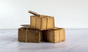 Tres cubos de jabón natural, atados con cuerda rústica, apilados sobre una superficie de mármol.