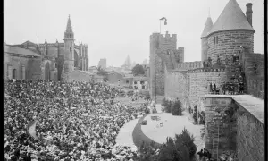Vue d'un spectacle dans les arènes de Carcassonne, avec une foule nombreuse assise et la cité médiévale en arrière-plan.