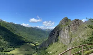 Un valle verde y montañoso con un arco natural en la roca, ideal para rutas circulares en Somiedo.