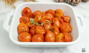 Tomates confitados en una fuente blanca, con ramitas de tomillo fresco. Un plato delicioso y aromático.