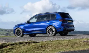 Błękitne BMW X7 M60i na tle malowniczego krajobrazu.