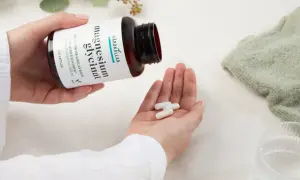 Händer häller upp tre kapslar magnesiumglycinat ur en flaska. Ett uppiggande medicin för nerver och energi.