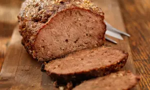 Un delizioso polpettone al forno, tagliato a fette su un tagliere di legno, pronto per essere gustato.